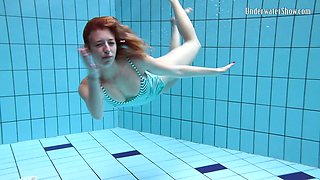 Playful redhead chick Anetta swims naked in the pool